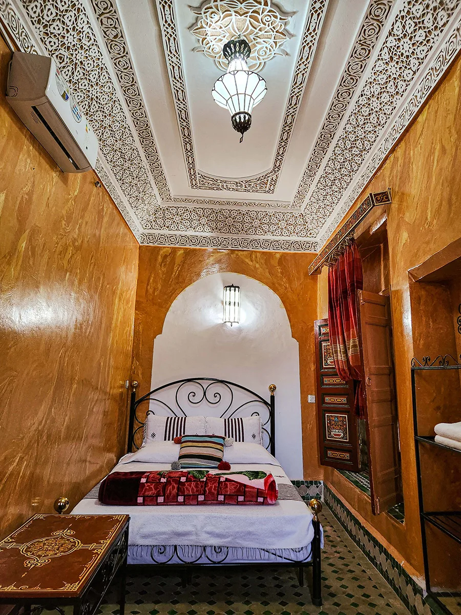 Authentic Classic Double Room in a Fez Riad featuring a double bed, intricate carved plaster ceiling, and traditional Moroccan