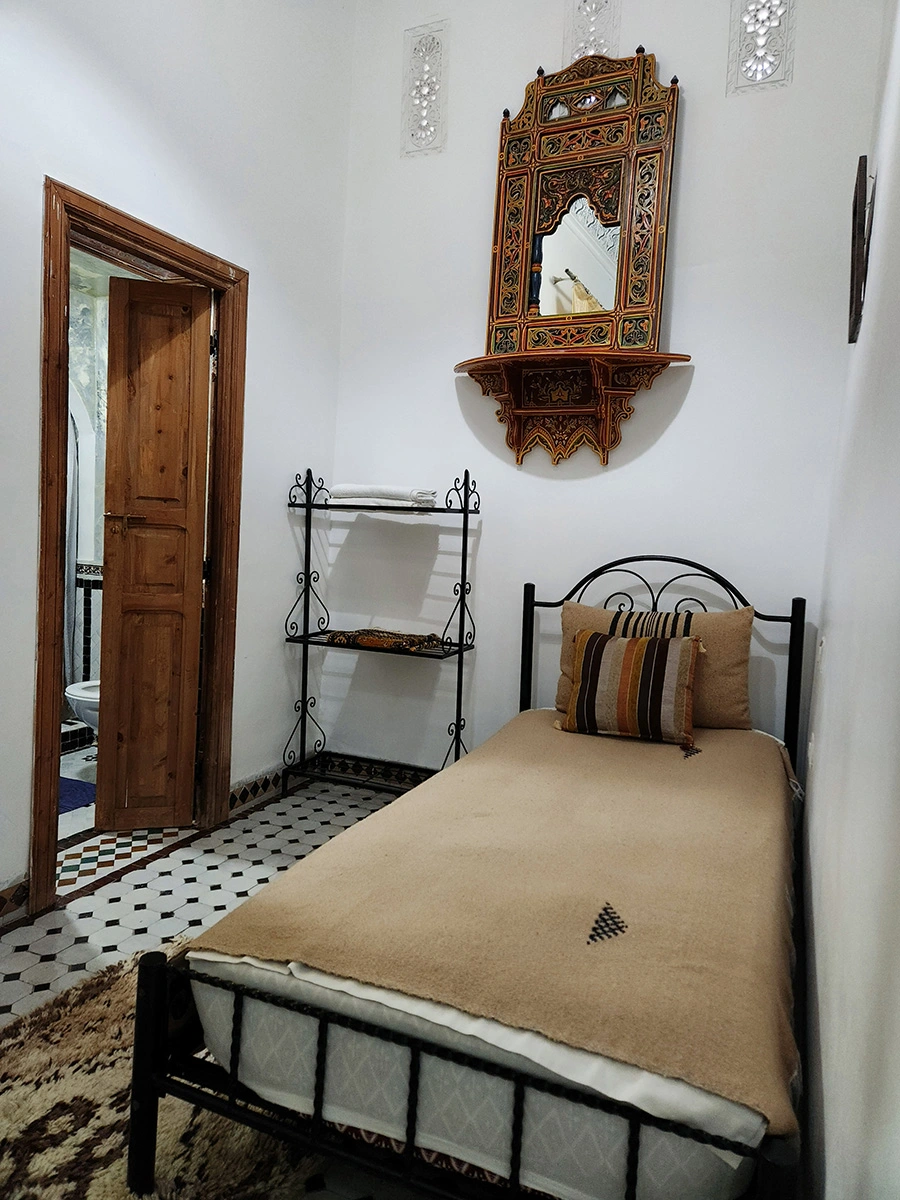 Single bed section of the Grand Family Suite with an authentic hand-painted Moroccan mirror and a view towards the private bathroom.